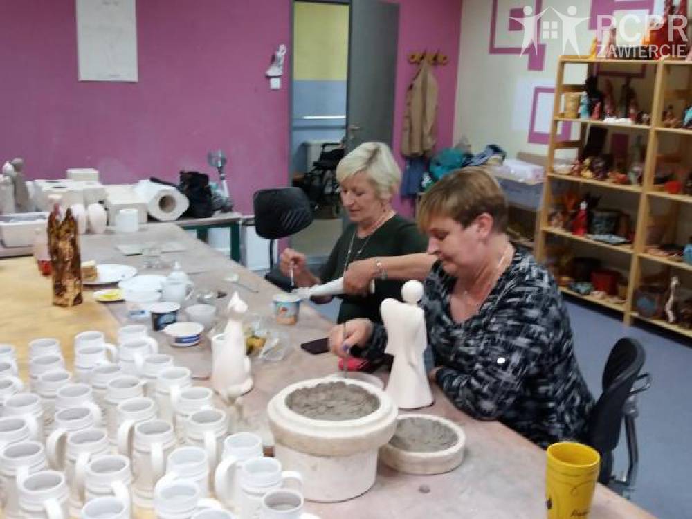 Zdjęcie: Dwie kobiety siedzą przy stole, na którym stoi wiele ceramicznych naczyń